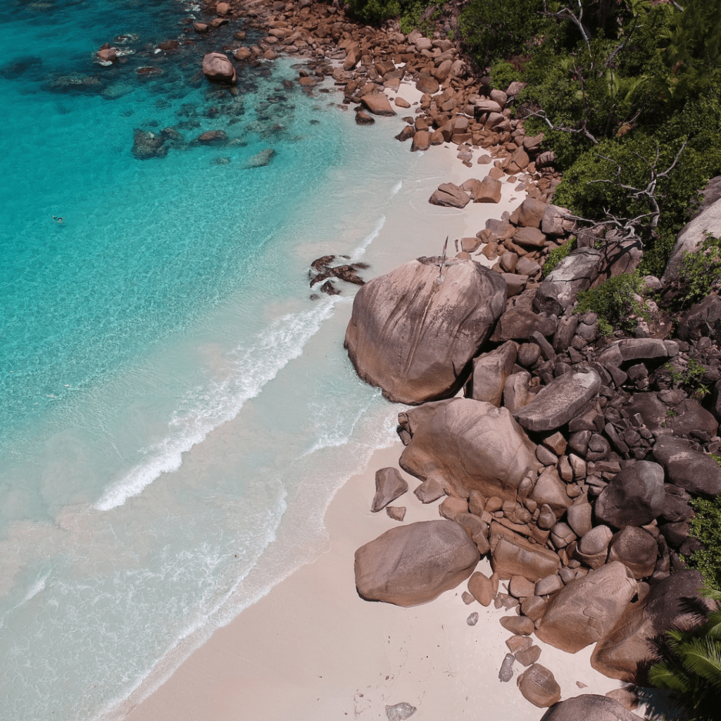 Aerial view of a beach in Seychelles with large boulders, clear turquoise water, and white sand Indian Ocean 1080x1080px