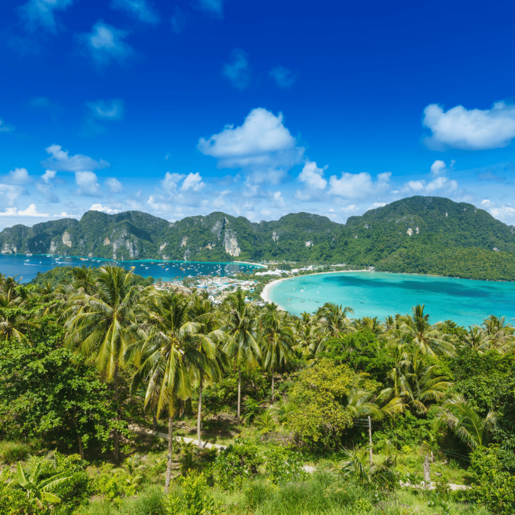 Panoramic view of Phi Phi Island in Thailand with lush palm trees, turquoise waters, and rugged hills 1080x1080px