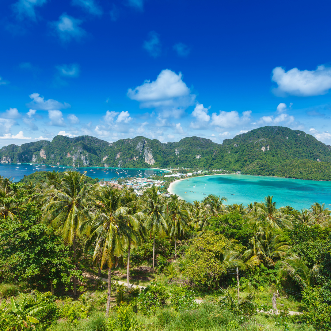 Panoramic view of Phi Phi Island in Thailand with lush palm trees, turquoise waters, and rugged hills 1080x1080px